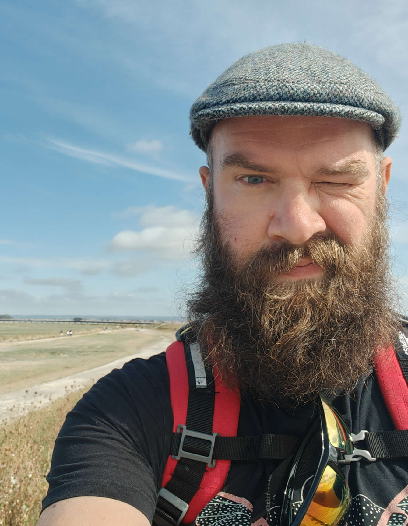 Davey Faherty squinting as he takes a selfie in front of a beach